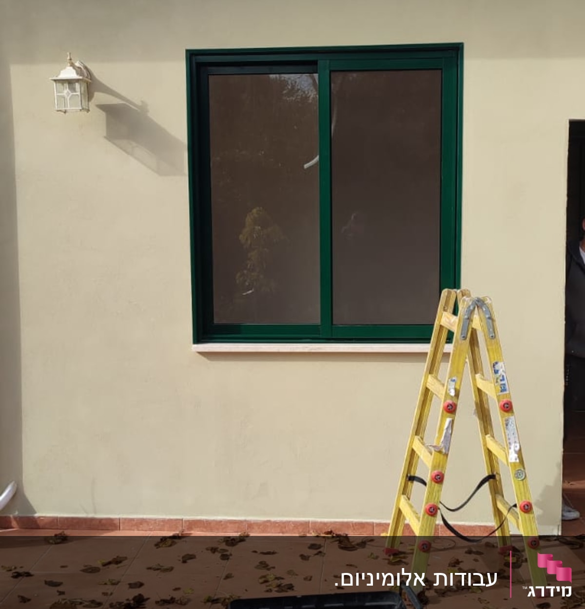 חלון אלומיניום עם מסגרת ירוקה על קיר חיצוני